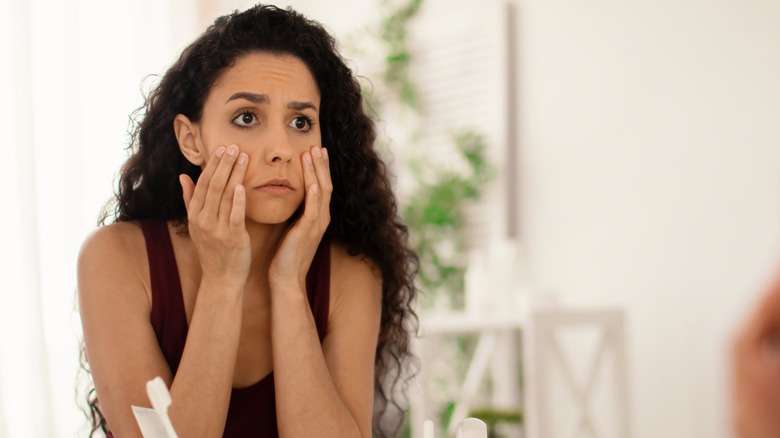 Woman examining undereyes in mirror