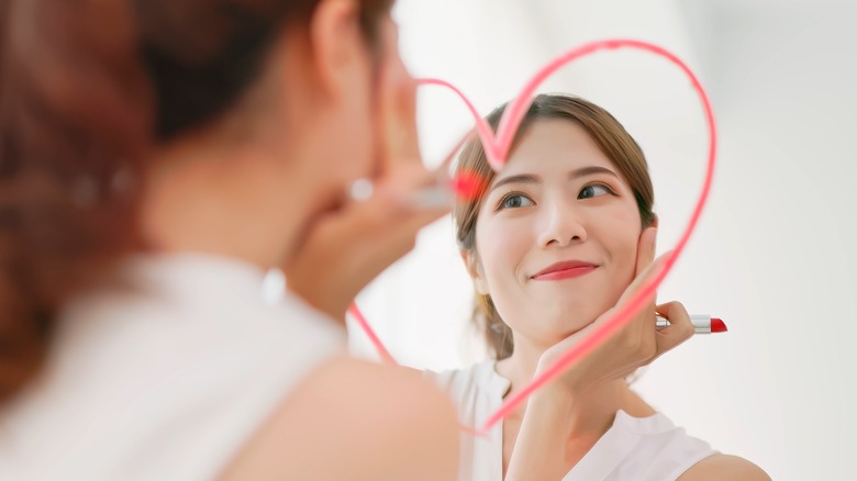 Woman drawing heart with lipstick