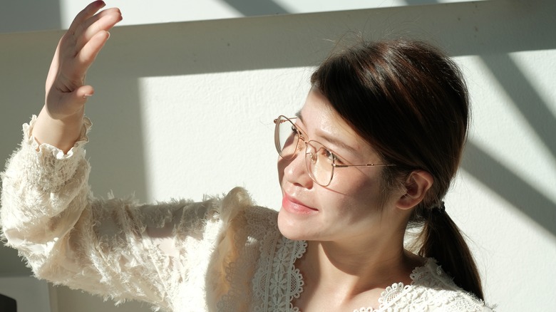 woman blocking sunlight through window