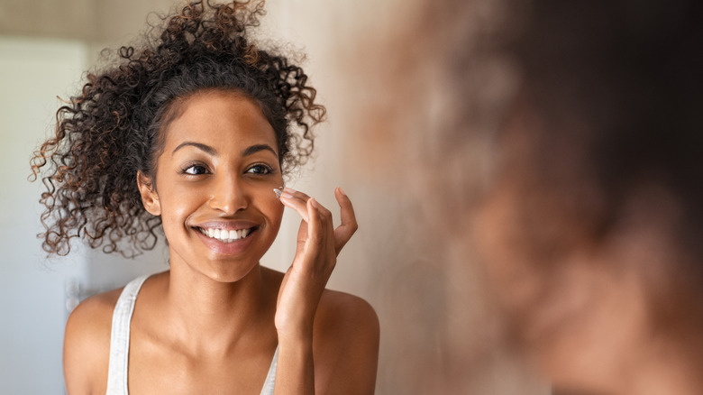 Woman dabbing on face cream in mirror