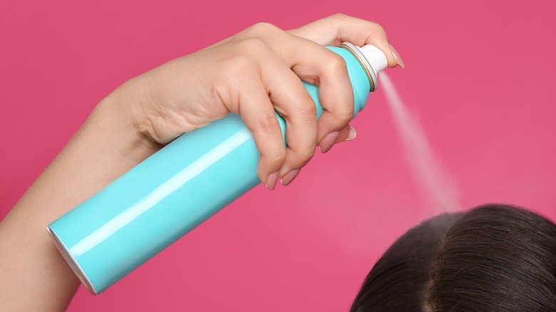 Woman spraying dry shampoo toward scalp