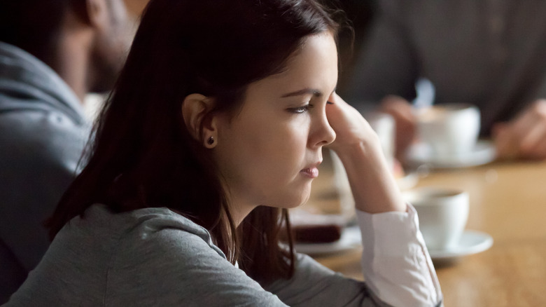 girl ignoring her friends cafe sitting alone