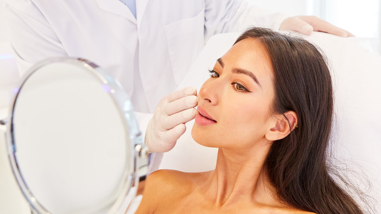 Woman observing post-procedural results in mirror