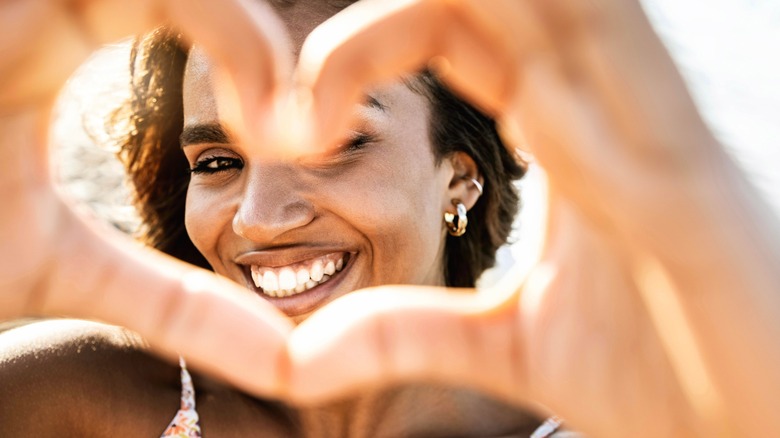 woman smiling through heart hands