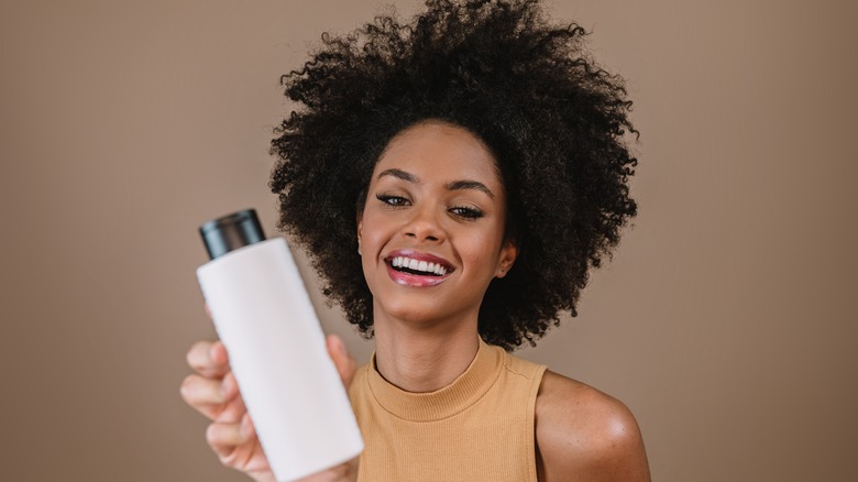 curly haired woman holding bottle