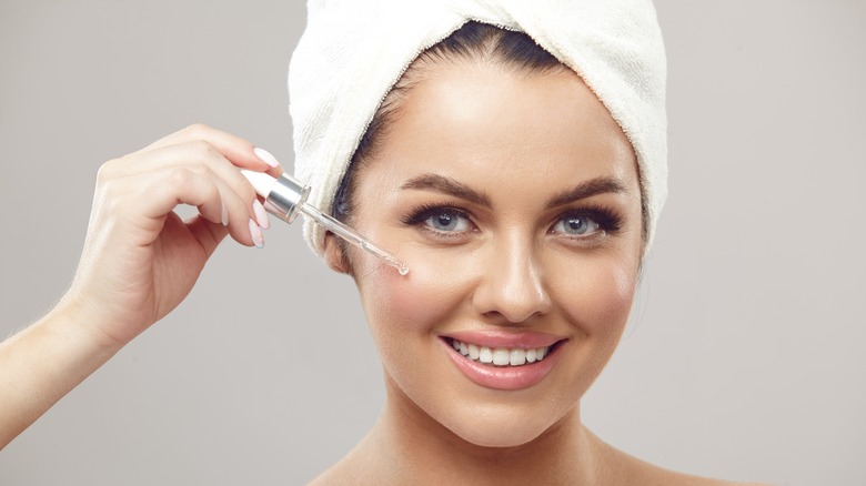 young woman putting serum on face