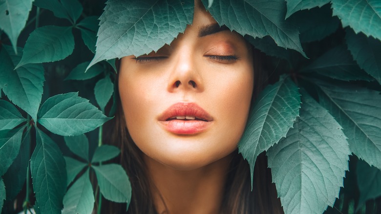 Woman surrounded by green leaves