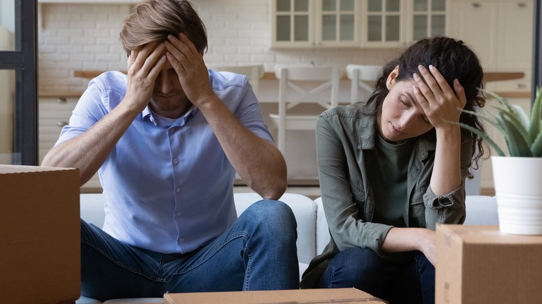 stressed-out couple covering their faces looking down