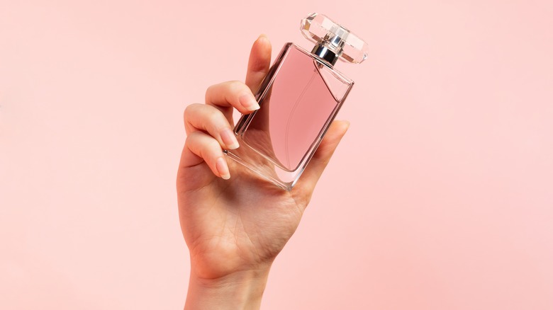 hand holding rose colored luxury perfume