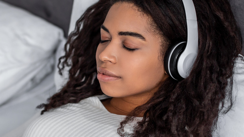 female in bed wearing headphones
