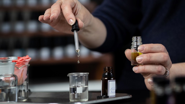 someone making perfume with test tubes and oils