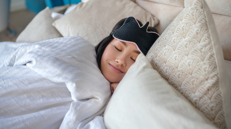 woman cozy in bed with sleeping mask
