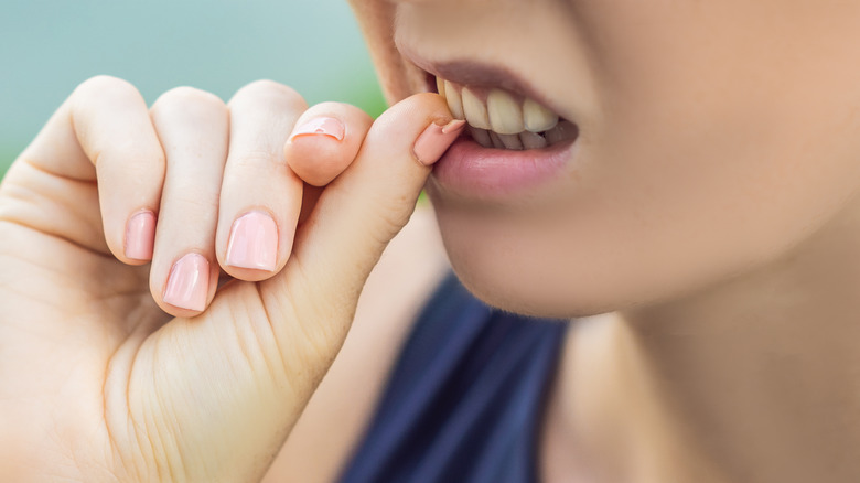 woman biting polished nails