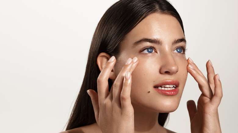 woman rubbing skincare on face