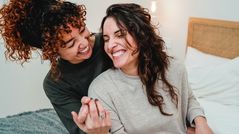 lesbian couple hugging and laughing in bed