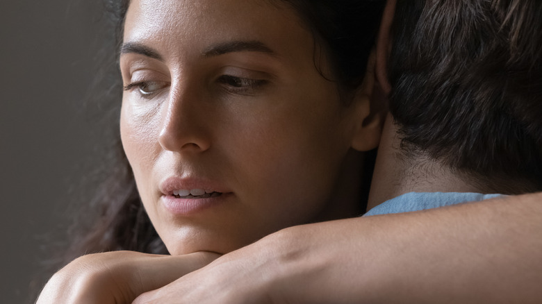 Woman hugging partner looking preoccupied