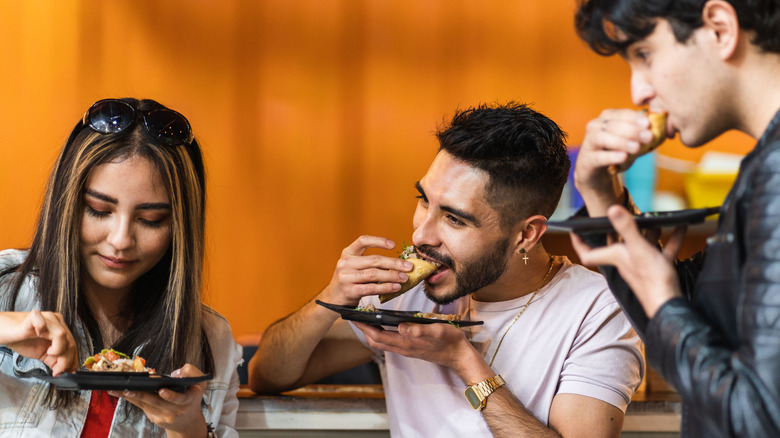 two men one woman eating