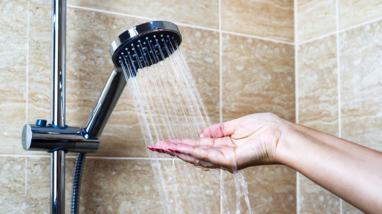 Woman's hands in cold shower 
