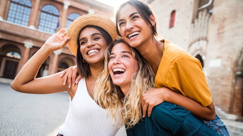 three women smiling together outside