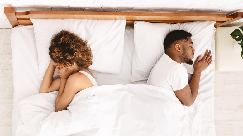 couple sleeping in bed with their backs to each other