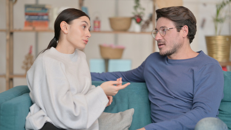 man and woman sitting on a couch, man listening to woman talk