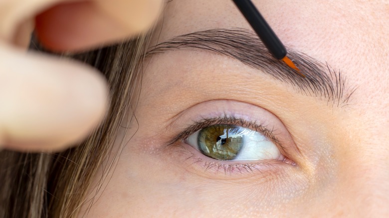 person applying eyebrow serum