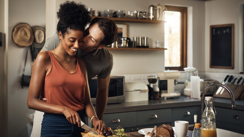 man kissing woman in kitchen
