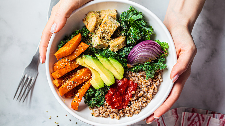 Person holding bowl of vegetables