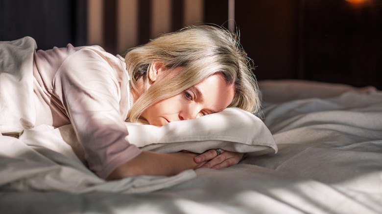 Woman hugging pillow on bed