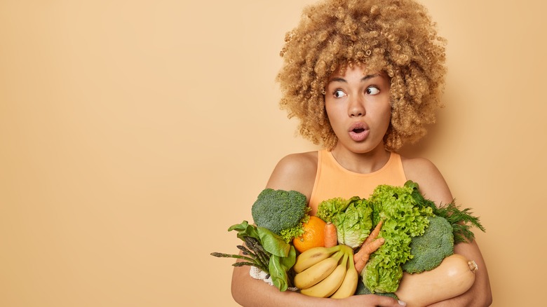 young woman with curly hair holding veggies