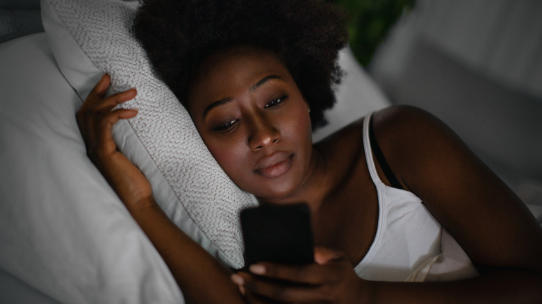 Woman looking at phone in bed
