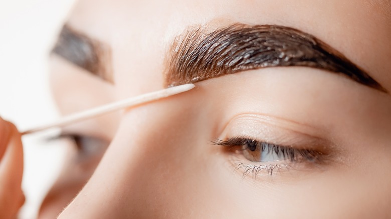 woman cleaning excess eyebrow tint