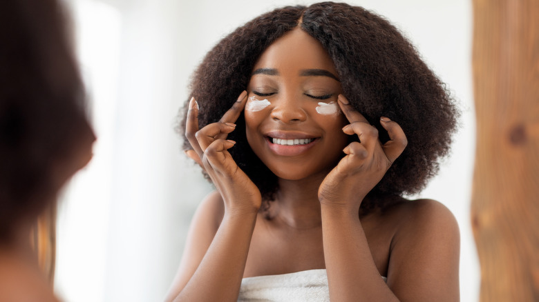 Woman applying moisturizer under eyes 