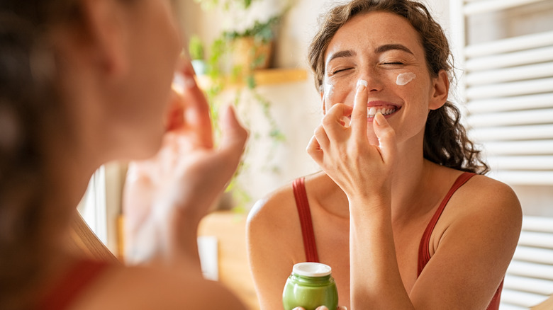 Woman applying moisturizer to nose