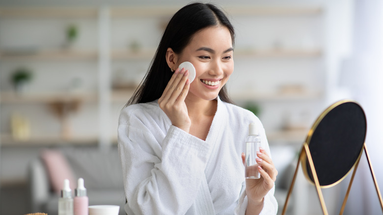 Woman applying toner with cotton pad