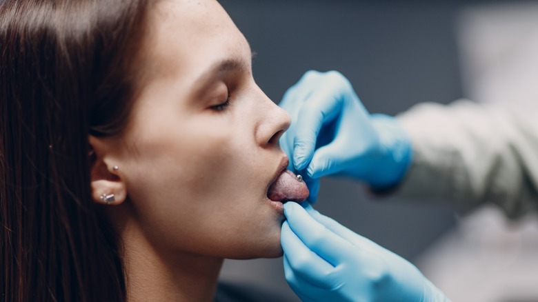 Woman getting tongue piercing adusted