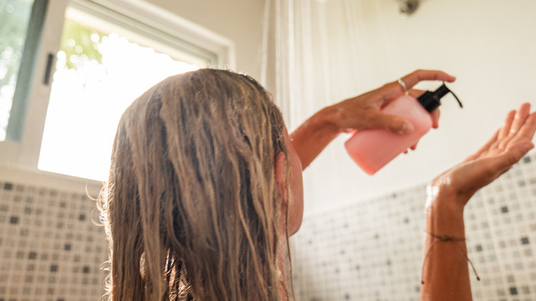 Woman applying conditioner on hair in the shower