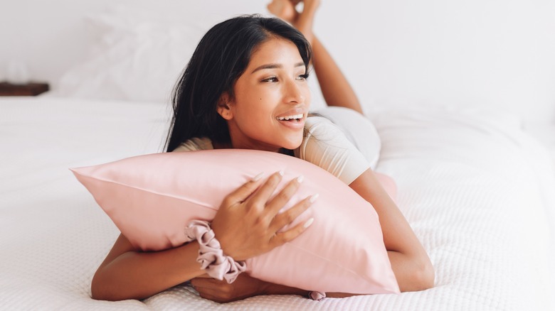 Smiling girl hugging pink pillow