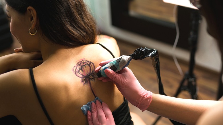 Woman getting spine tattoo