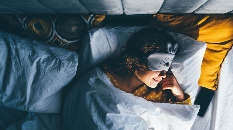 Woman wearing bunny sleep mask in bed