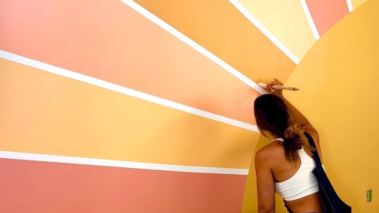 woman painting mural accent wall