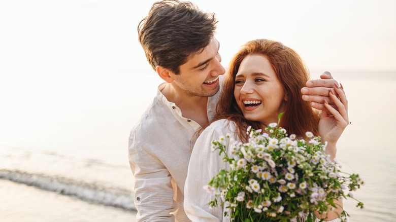 couple at the beach holding a bouquet of flowers