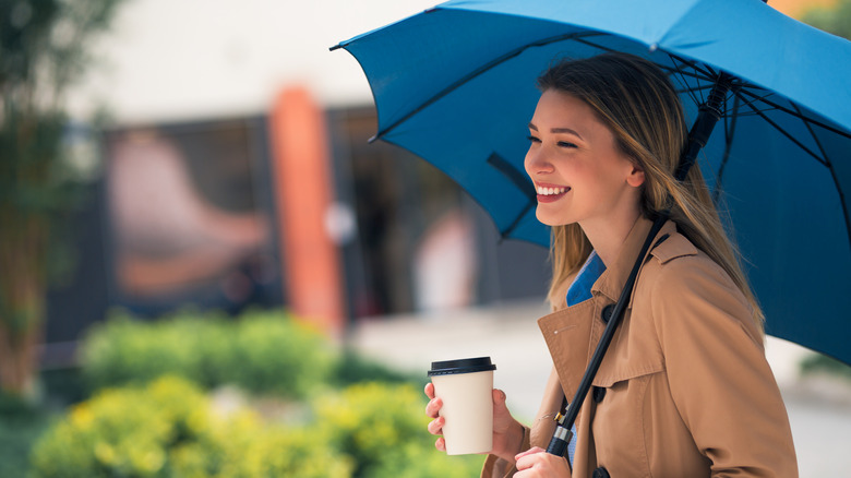 Woman walking with coffee and umbrella