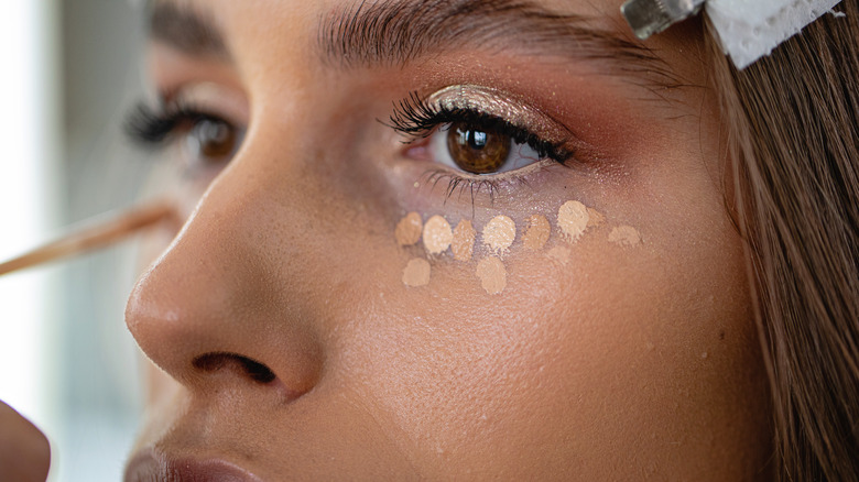 woman applying under eye concealer