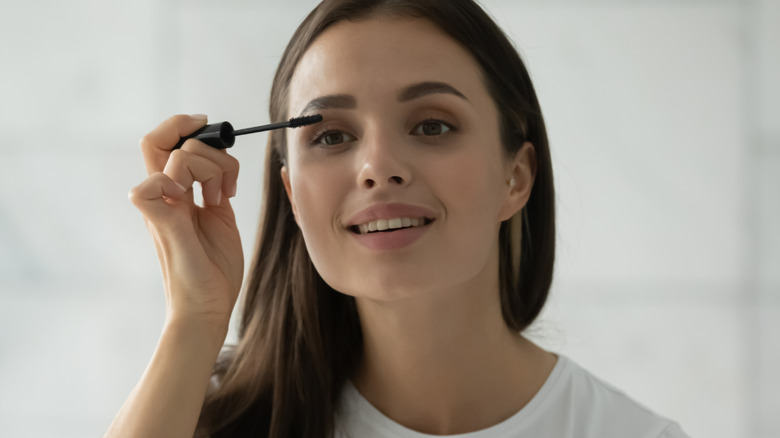 smiling woman applying mascara