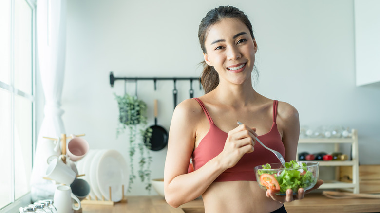 Woman eating salad in workout clothes 