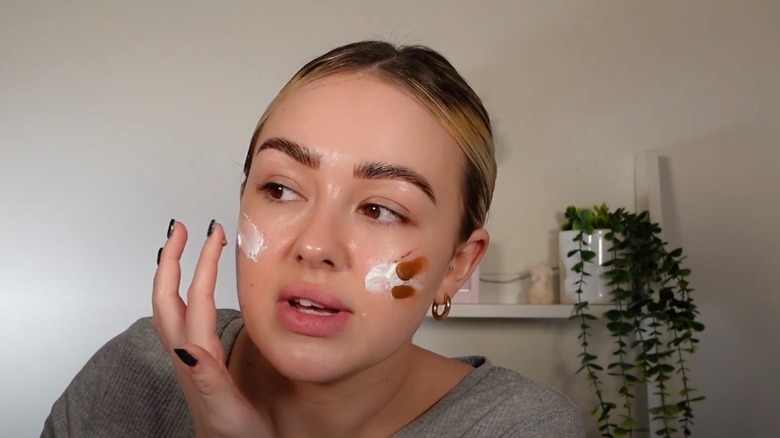 woman mixing bronzing drops with moisturizer