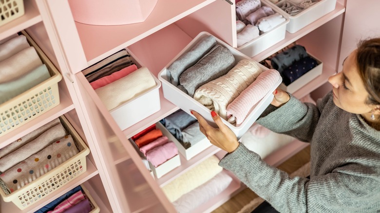 woman organizing closet with storage bins and drawers