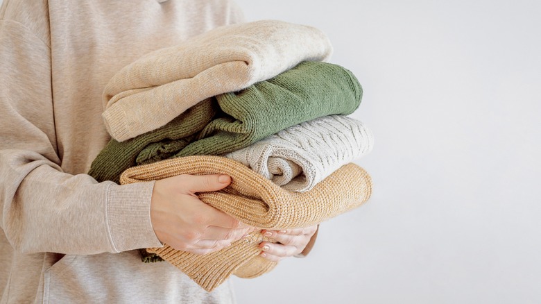 woman holding stack of clothes