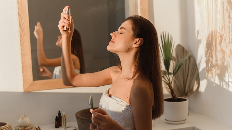 Woman spraying product on face